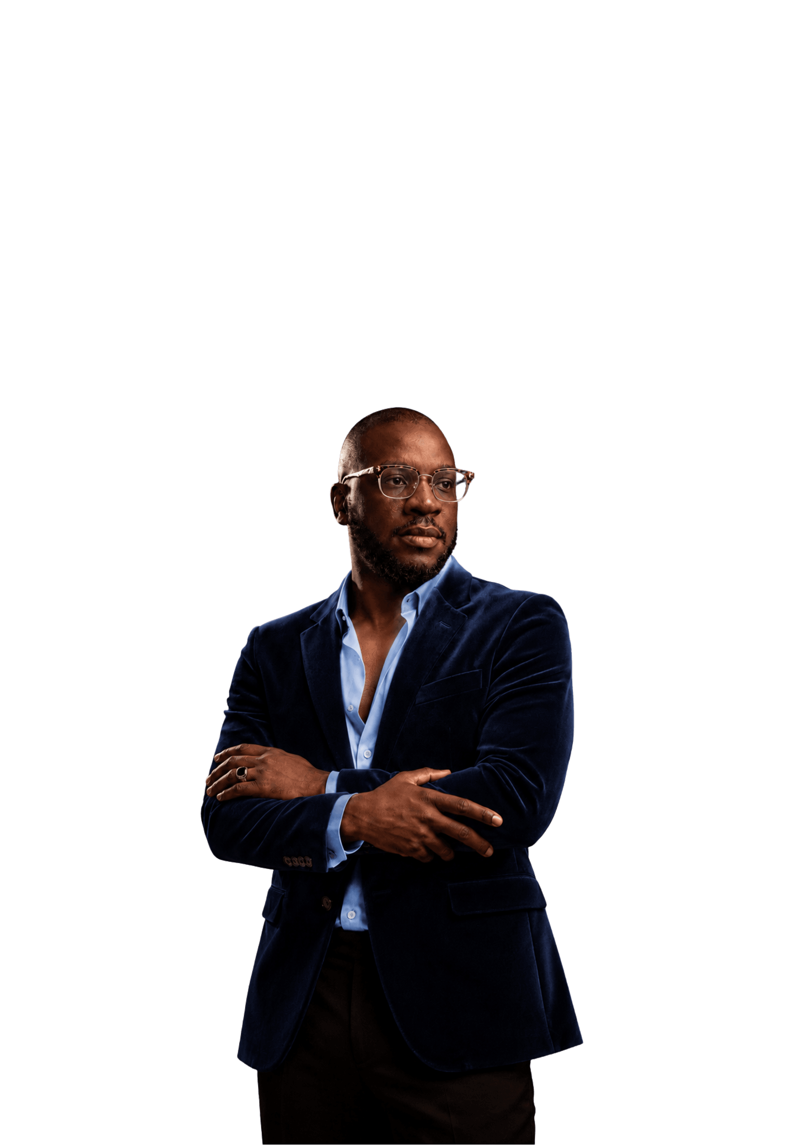 Jed Ibekwe standing with his arms crossed, in a navy velvet blazer over an open-collar shirt